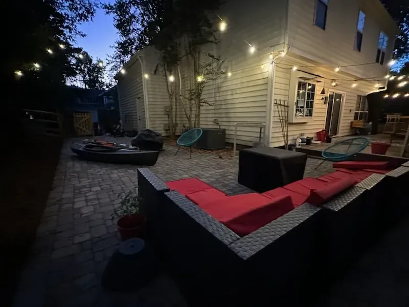 A patio with a lot of furniture and a fire pit at night.