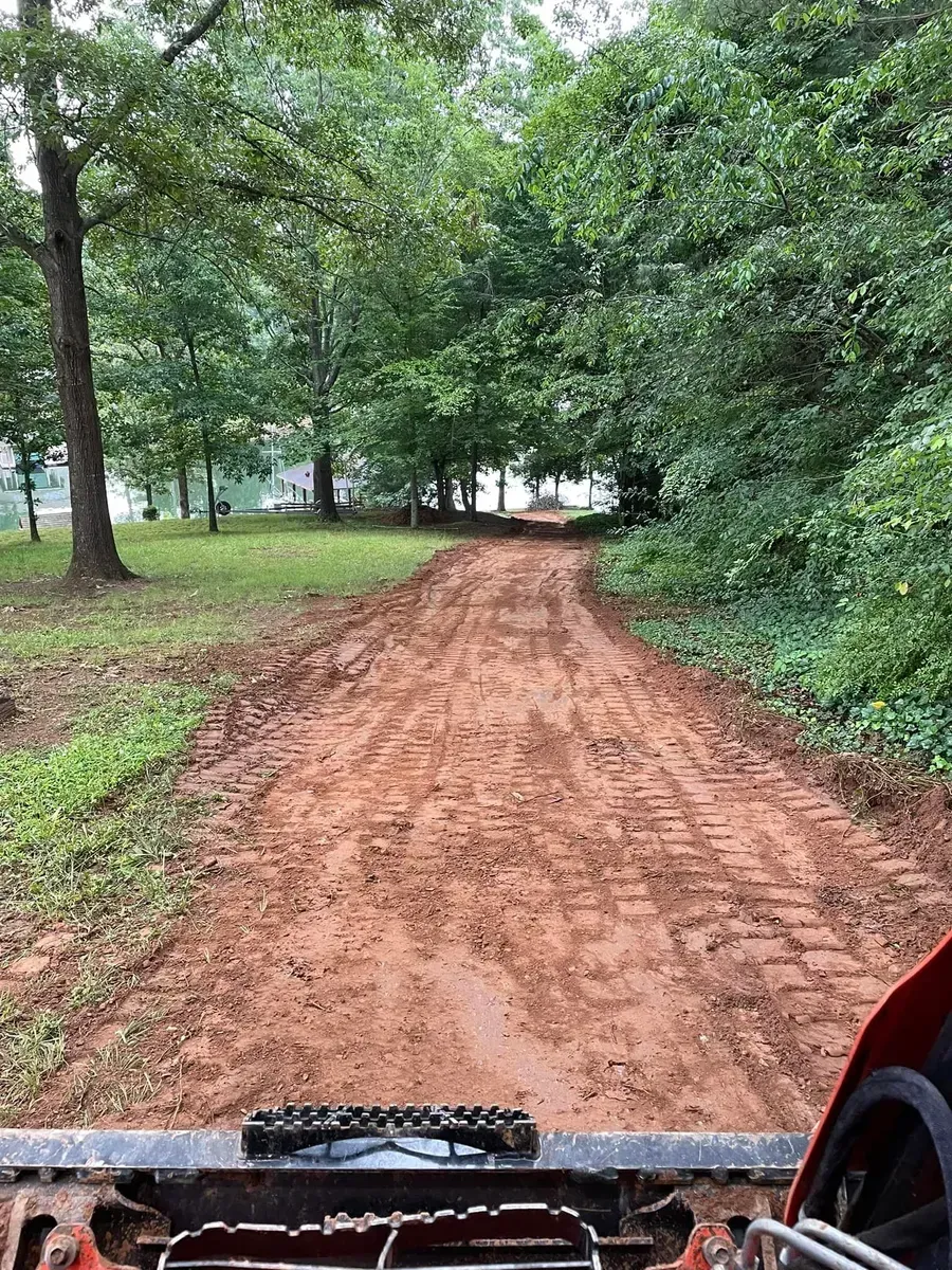 A person is driving a tractor down a dirt road.