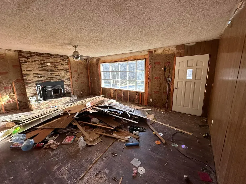 A living room with a fireplace and a lot of trash on the floor.
