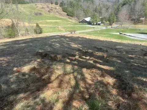 A large pile of dirt is sitting on top of a hill next to a golf course.