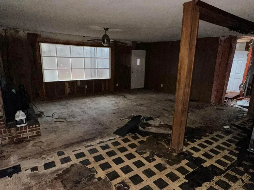 An empty living room with a ceiling fan and a window.