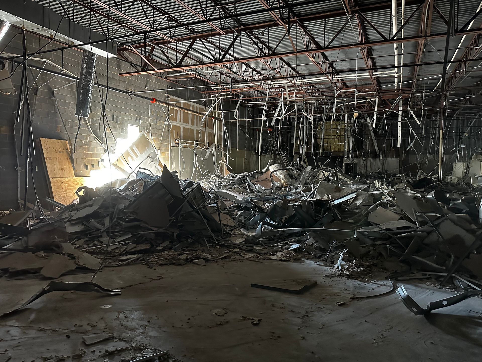 Interior of a building heavily damaged by fire, debris scattered across the floor, structural elements exposed.