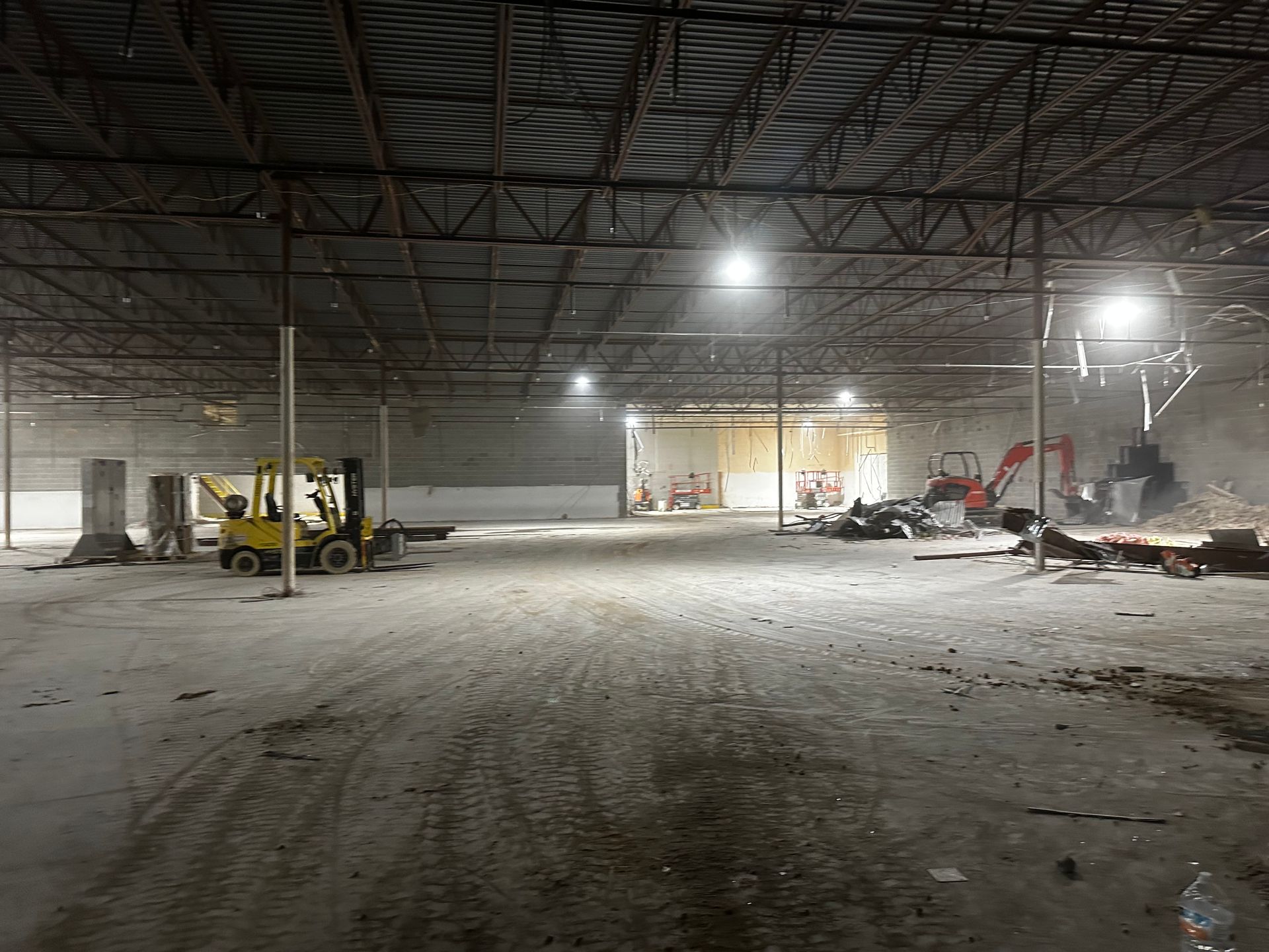 Interior of a large industrial building during demolition. Construction equipment and debris present.