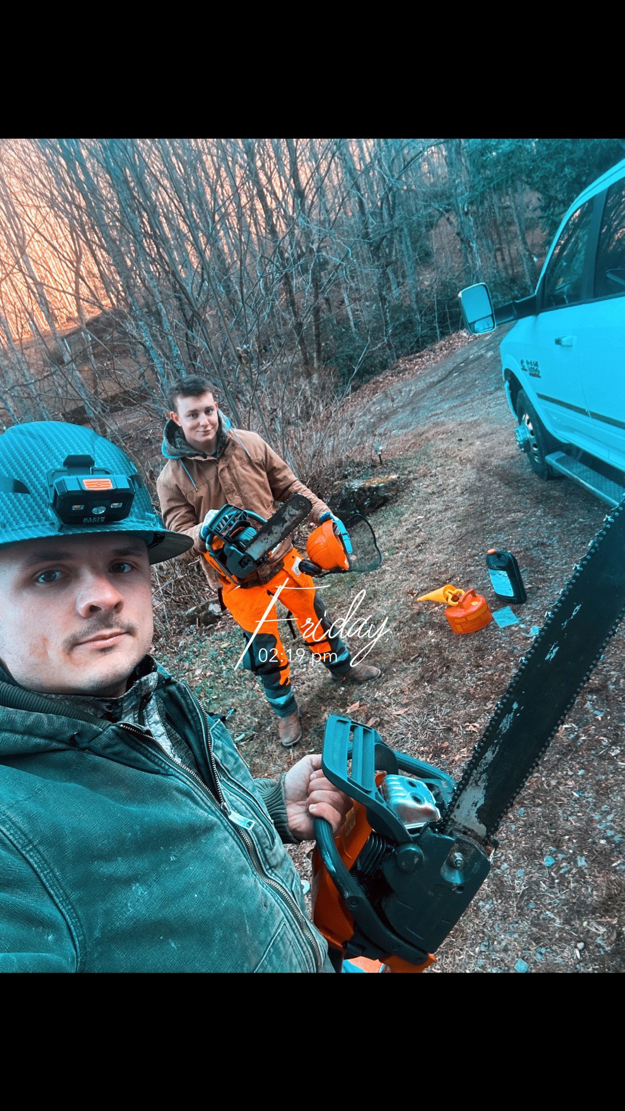 A man is holding a chainsaw in front of a car.