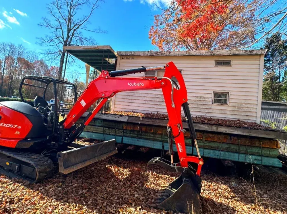 A small red excavator is parked in front of a house.