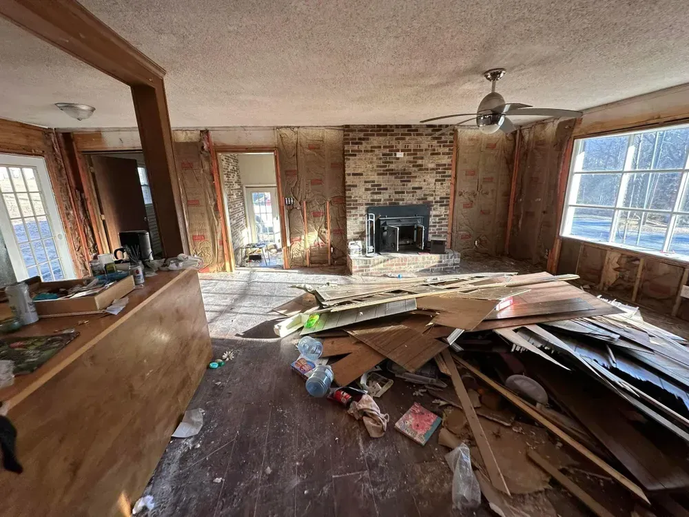 A living room with a fireplace and a lot of trash on the floor.