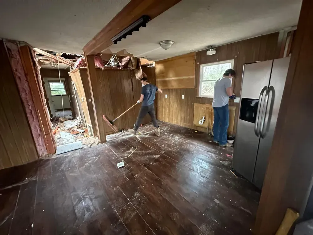 Two men are working in a kitchen with a refrigerator.