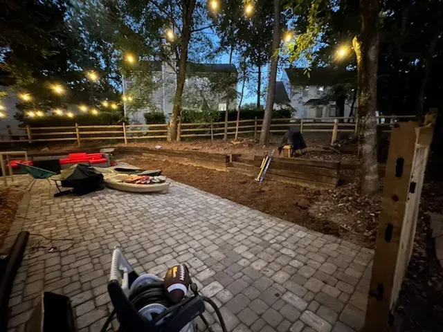 A stroller is sitting on a brick patio in a backyard.