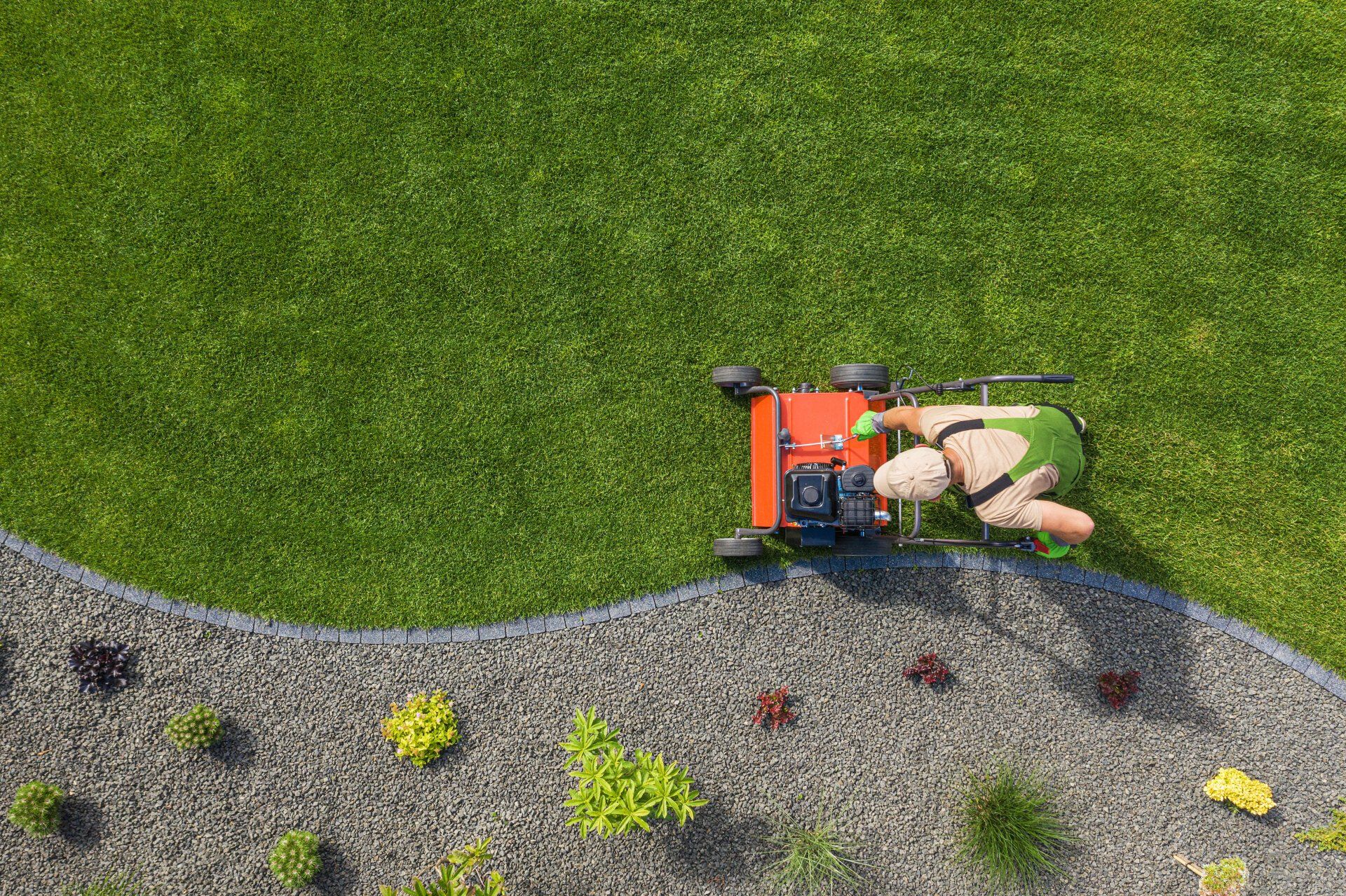 Top view of a gardener mowing the lawn
