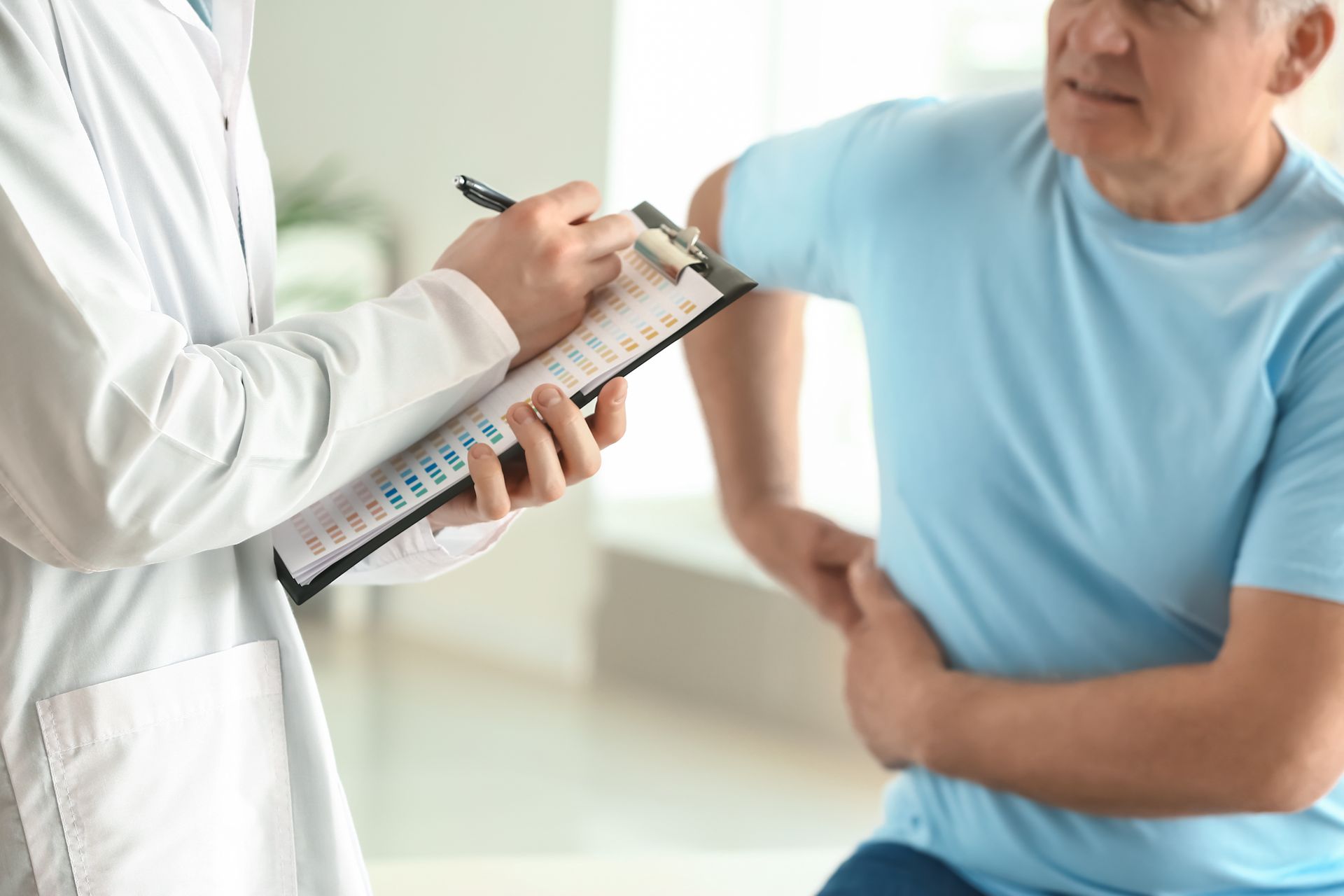 Healthcare professional writing on a clipboard while with patient during a checkup.