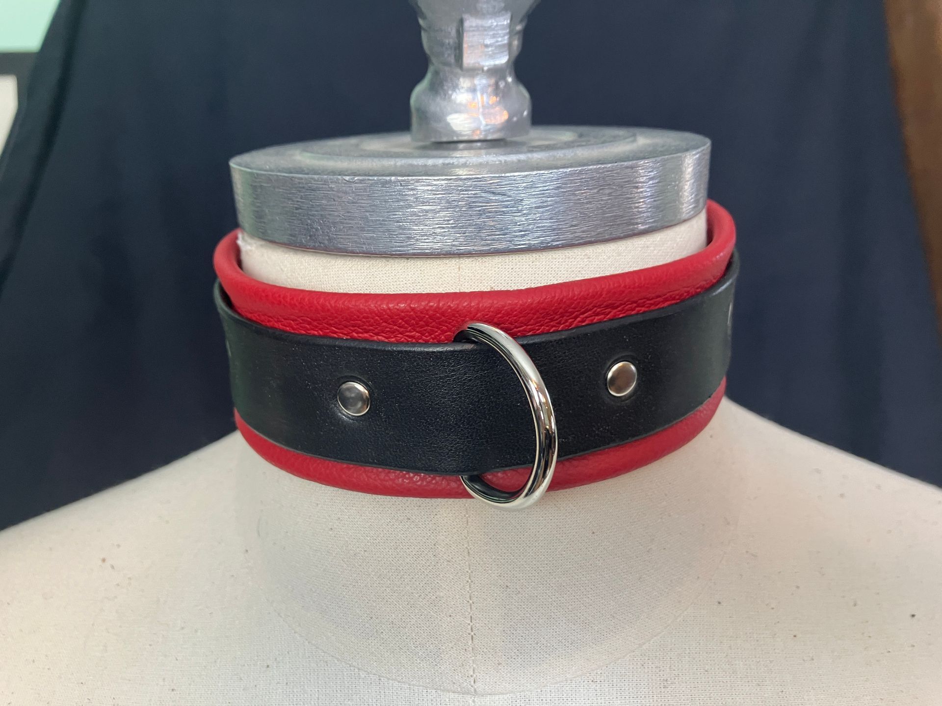 Black and red leather collar with a silver ring, on a mannequin neck.
