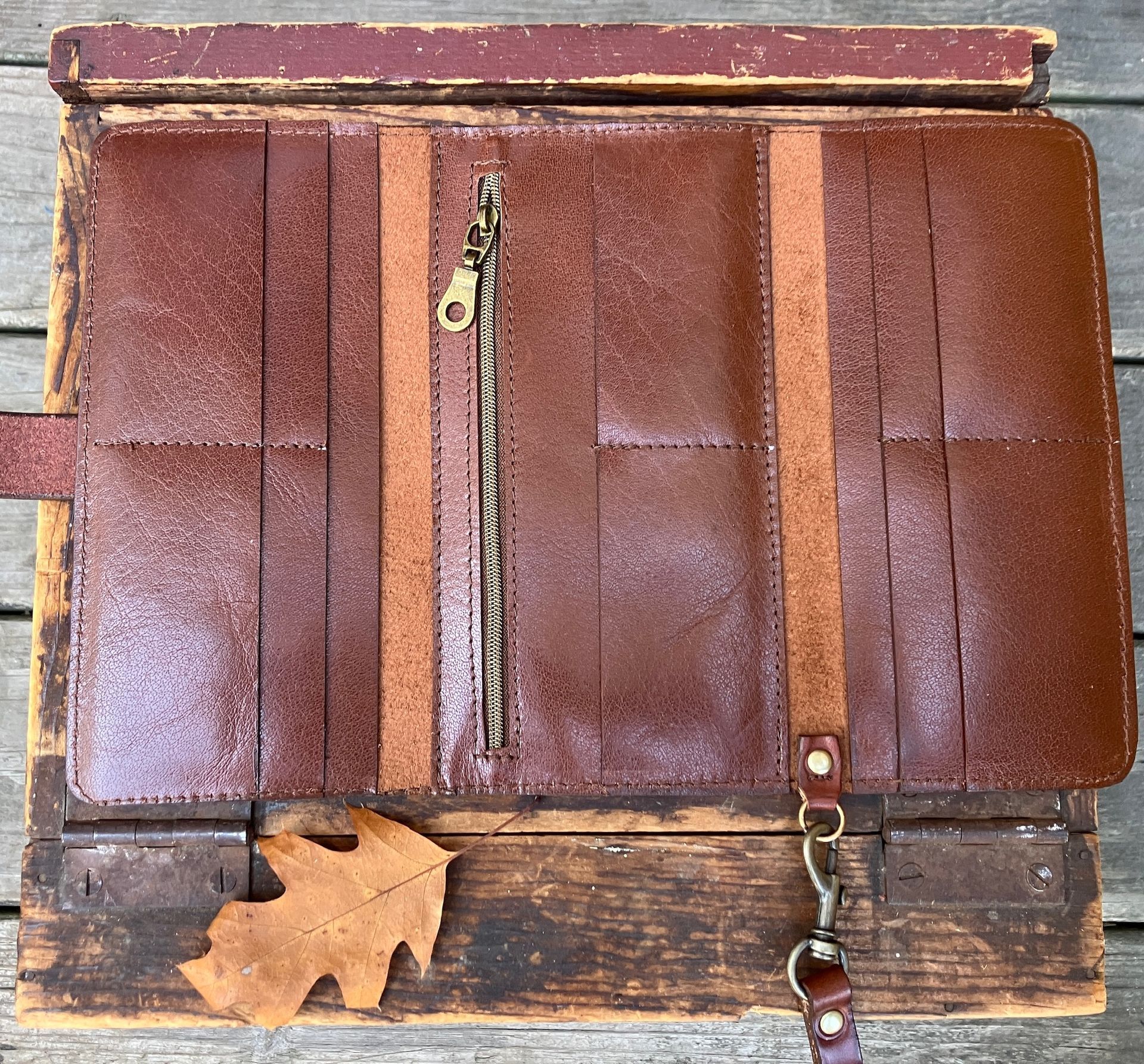 A trifold "ladies" wallet with clutch strap and zippered coin section