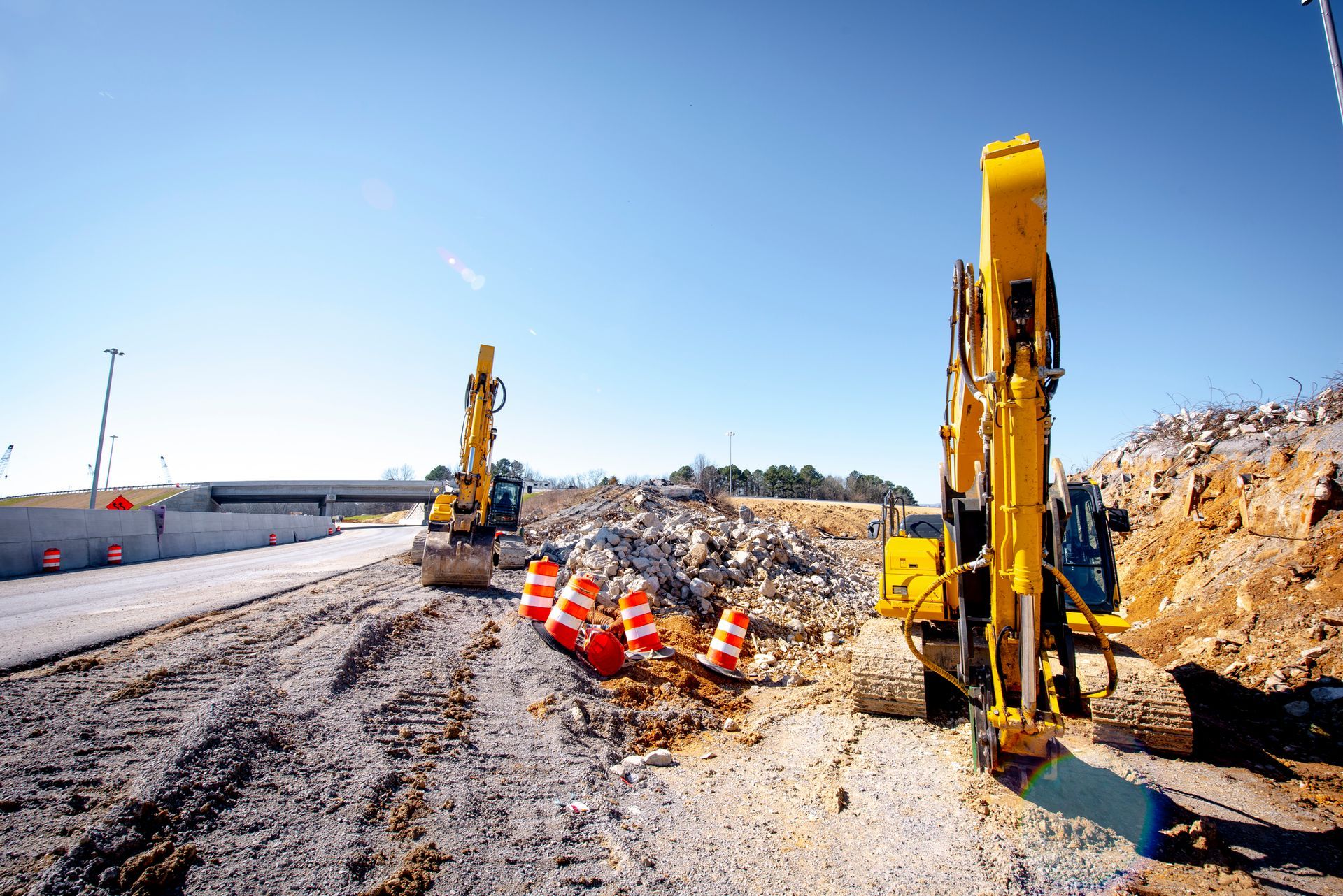 Two yellow excavators are working on a construction site.