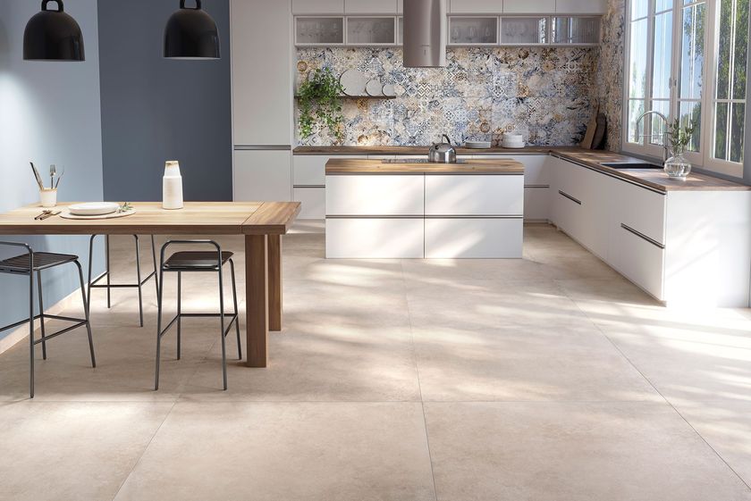 Una cucina luminosa e moderna con tavolo in legno e due sgabelli, mobili bianchi e piastrelle decorative a parete come rivestimento.
