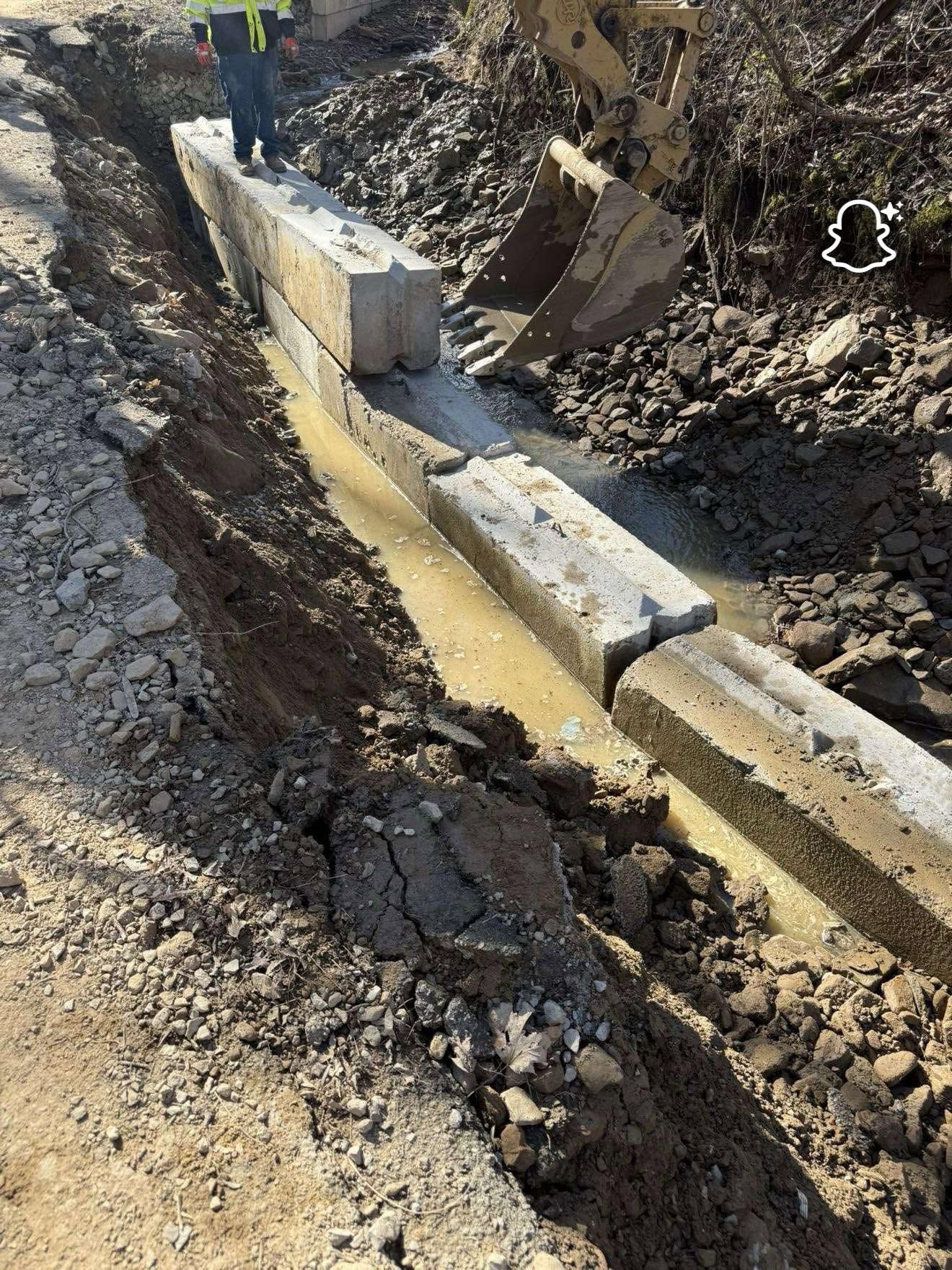 Construction trench with a concrete drainage channel and muddy water running through it