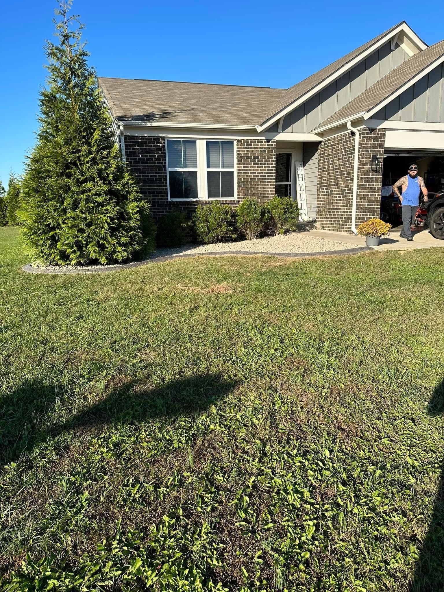 Suburban house with stone facade, large green lawn, and two people standing near the front door
