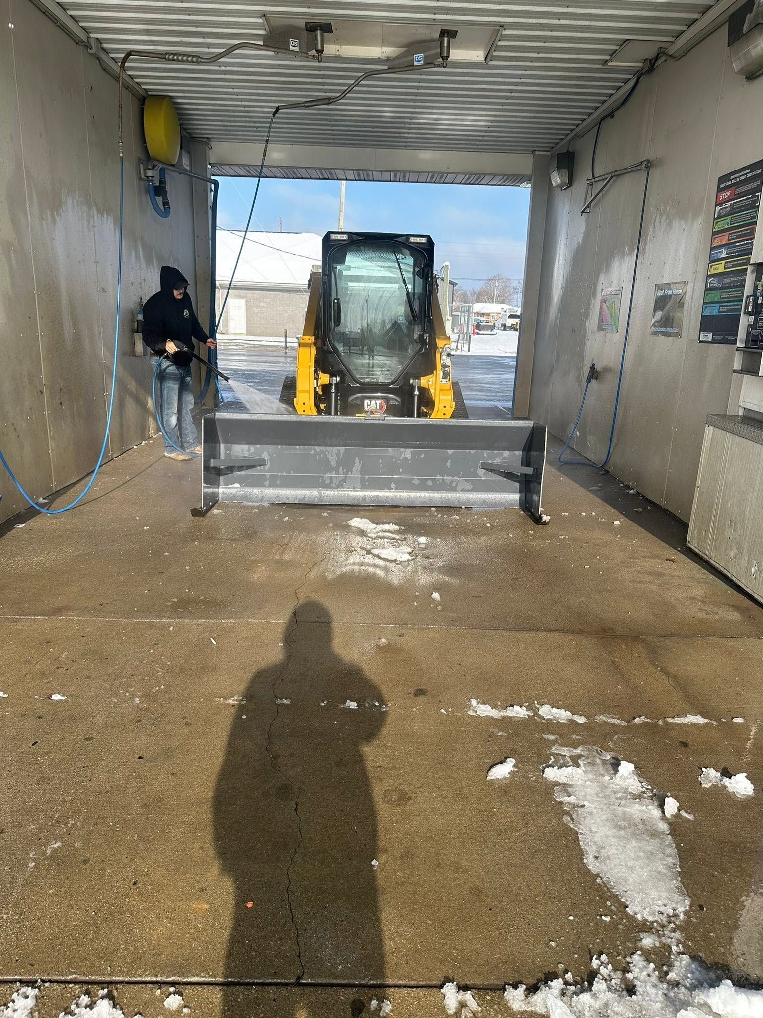 Loader inside a car wash tunnel, facing out toward a snowy lot.