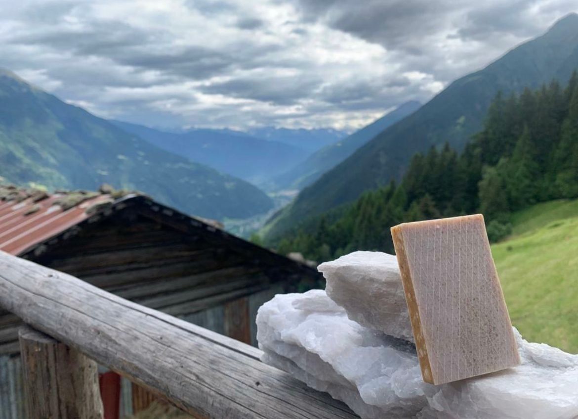 Saponetta su rocce bianche, ringhiera in legno e vista sulla valle di montagna.