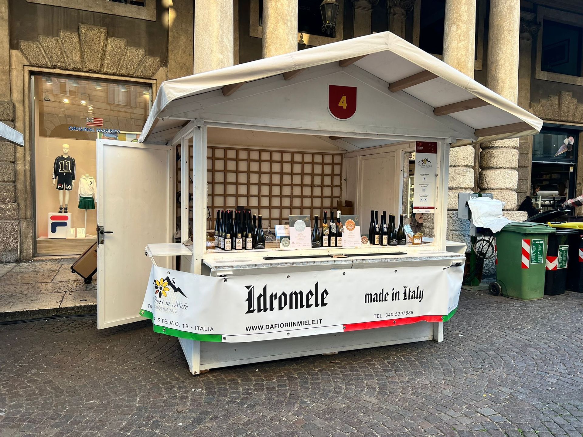 A white outdoor stall sells bottles of 
