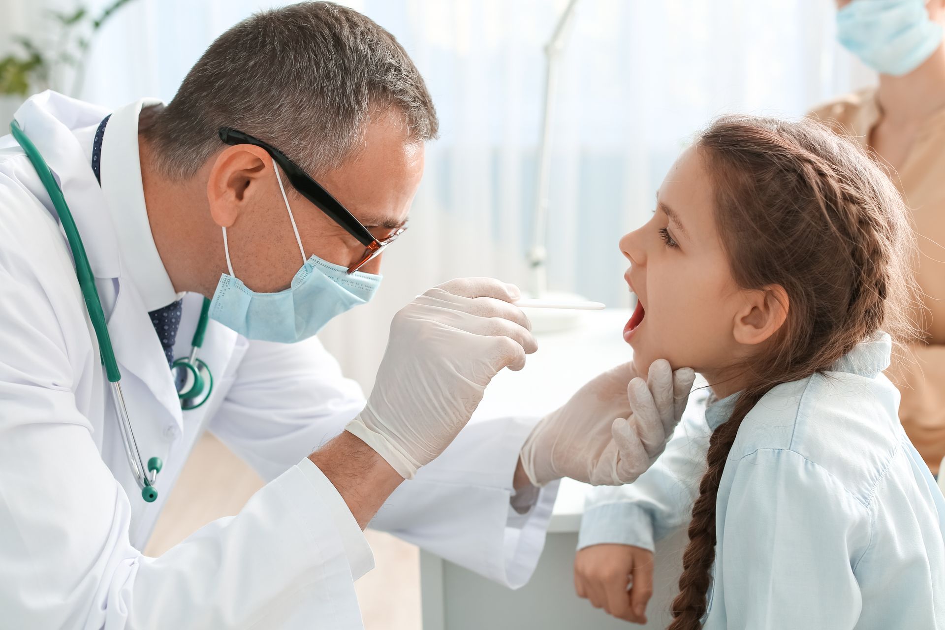 Doctor checking girl's throat at urgent care Doctor checking girl's throat at urgent care