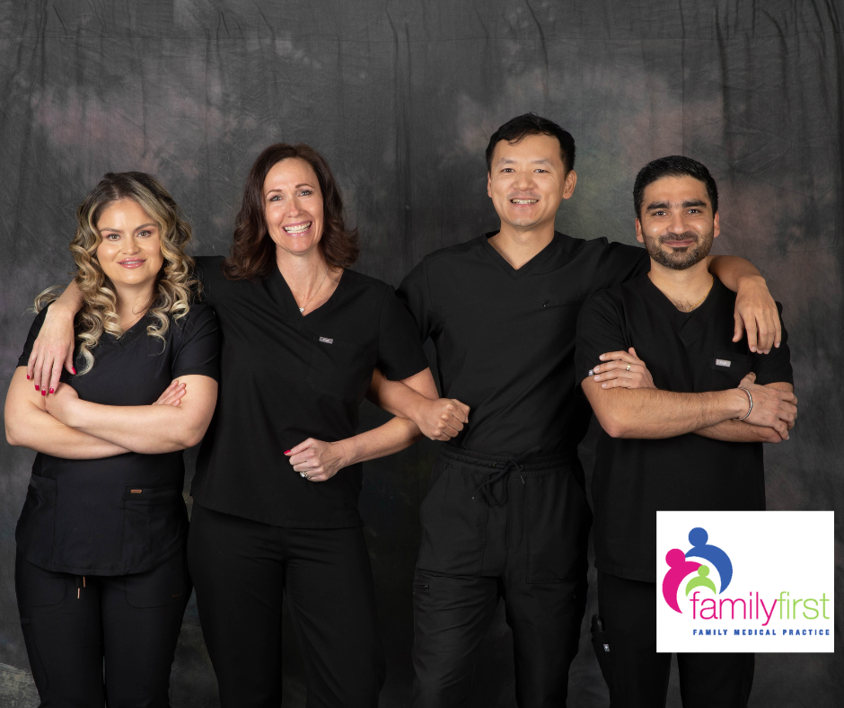 Four healthcare providers in black scrubs posing with arms around each other in front of a gray backdrop; Family First logo.