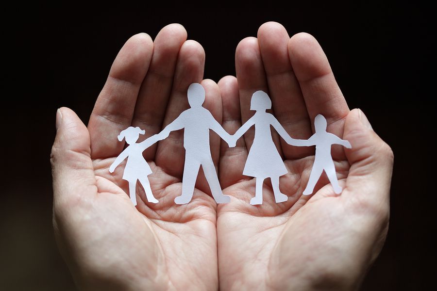 Hands Holding A Paper Cut-Out Chain Of A Four-Person Family Hands Holding A Paper Cut-Out Chain Of A Four-Person Family