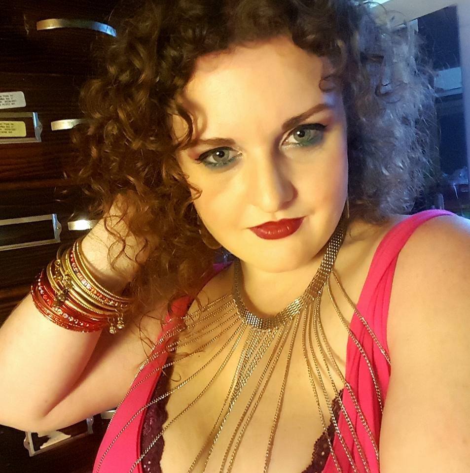 A woman with curly hair wearing a necklace and bracelets