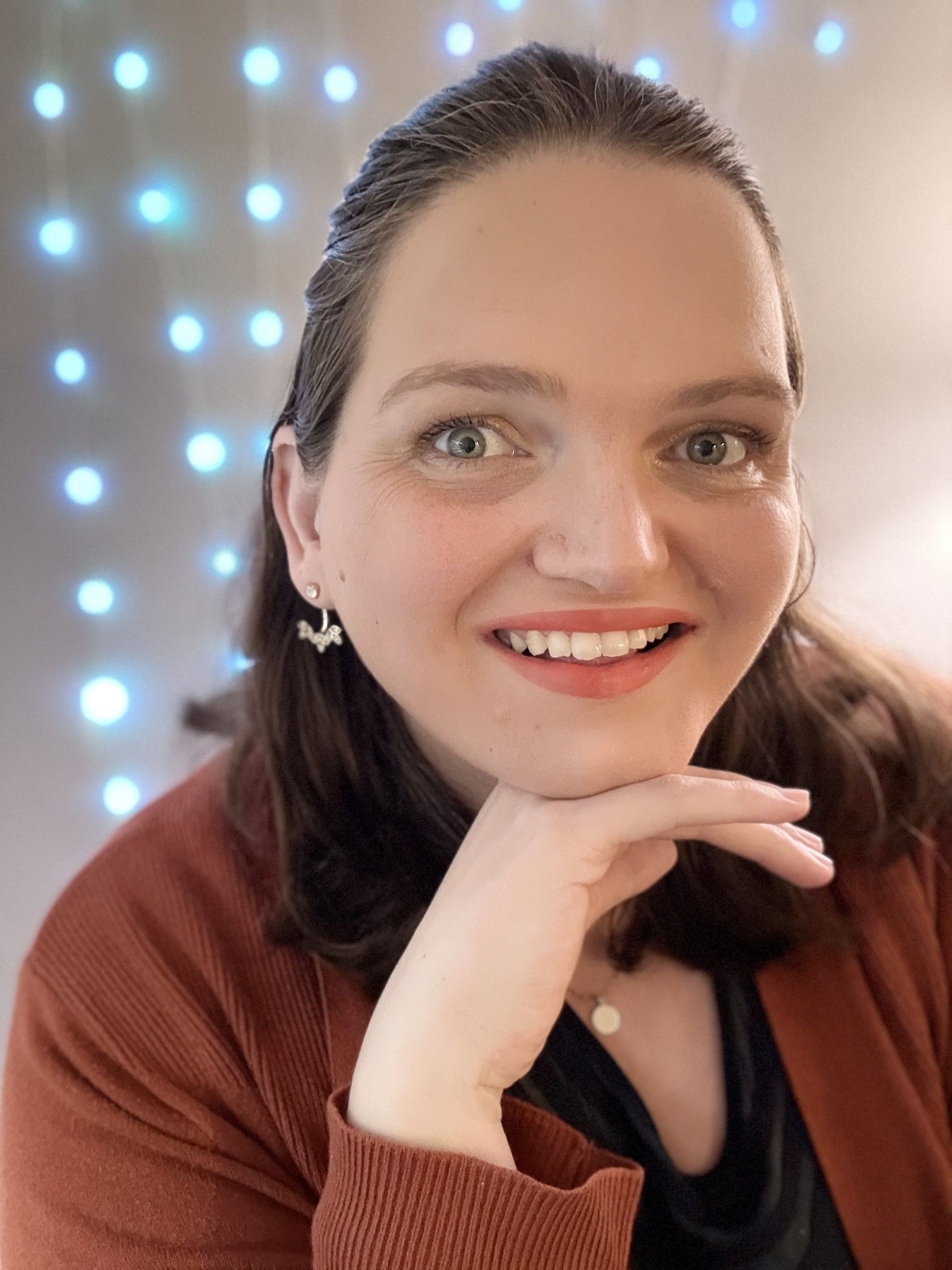 A woman is smiling with her hand on her chin.