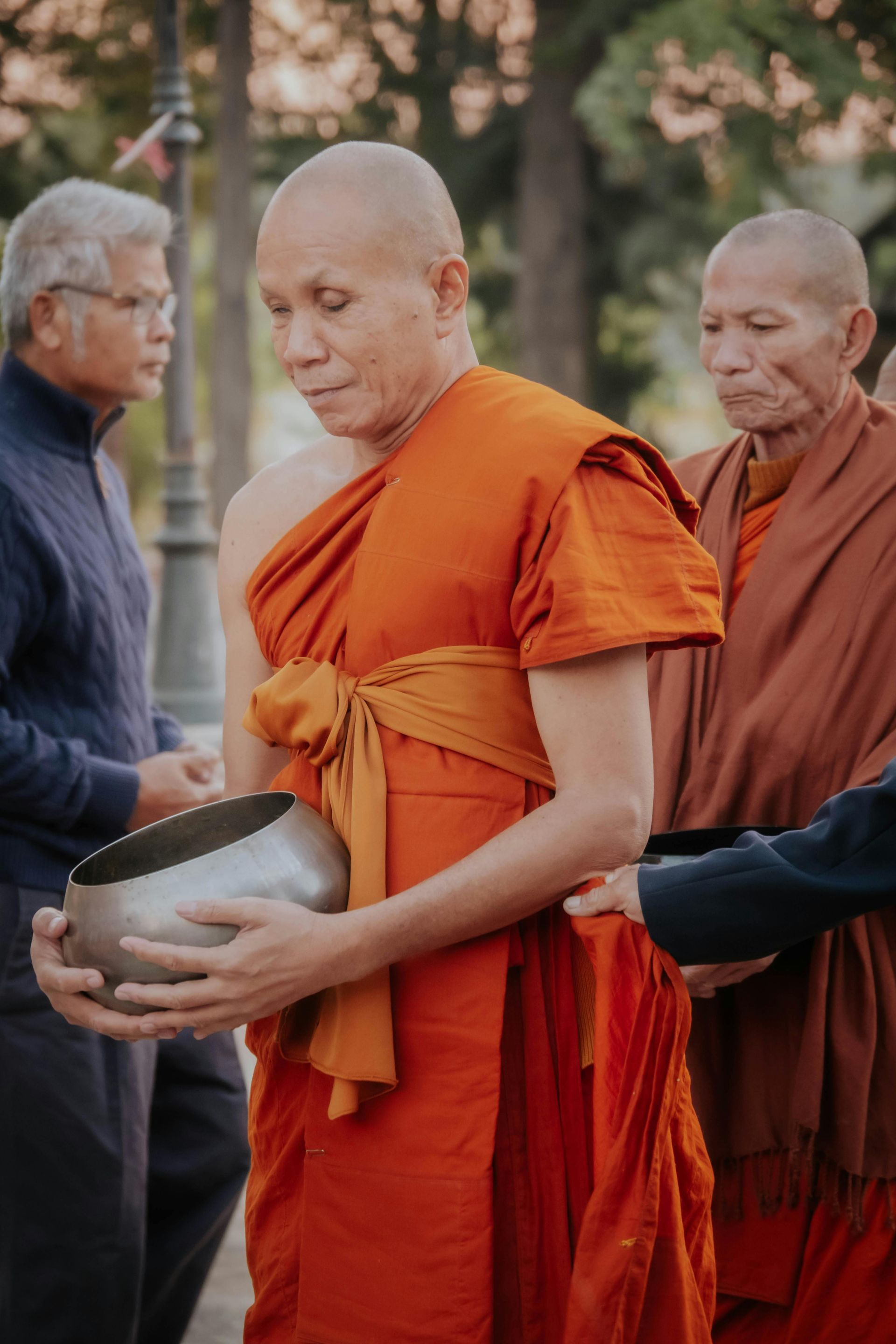 A group of monks are standing next to each other holding bowls.