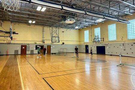 A group of people are playing basketball in an empty gym.