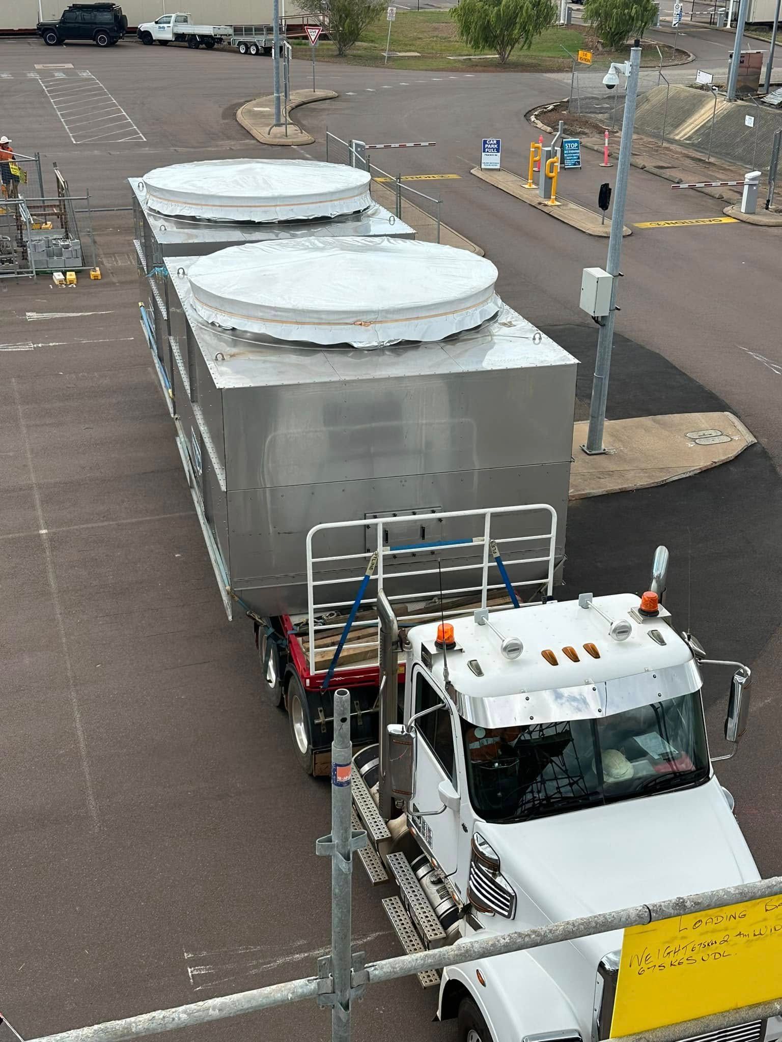 A truck transports a large, metallic industrial tank with round tops on a road — Great Northern Airconditioning & Mechanical Services in Berrimah, NT