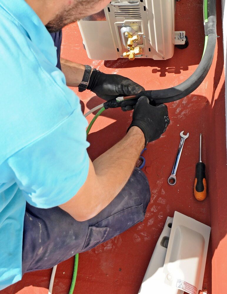 Man in Blue Shirt Fixing Aircon — Great Northern Airconditioning & Mechanical Services in Berrimah, NT