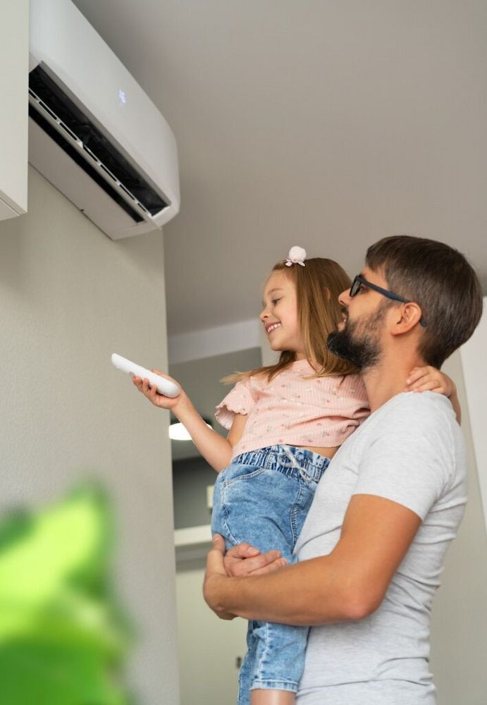 Man Holding Girl With Remote — Great Northern Airconditioning & Mechanical Services in Nightcliff, NT