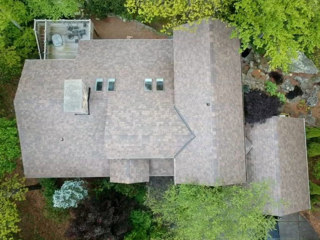 Aerial view of a house with a gray roof surrounded by trees and greenery