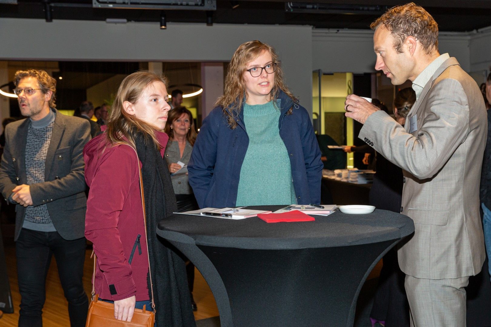 Mensen die met elkaar praten aan een hoge tafel tijdens een netwerkevenement binnenshuis.