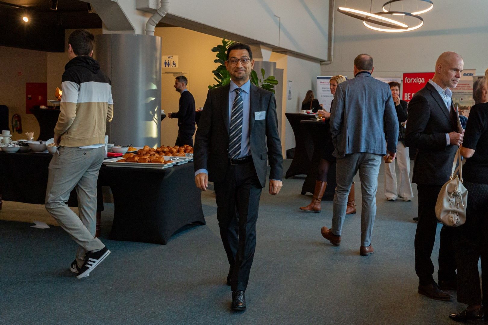 Zakelijke bezoekers mengen zich in een moderne lobby met een fruittafel en drankjes bij een receptie.