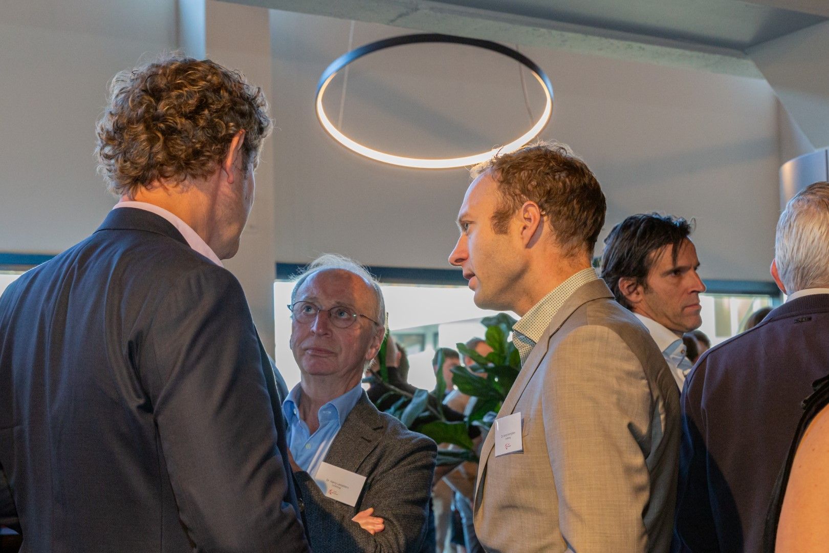 Mensen die met elkaar in gesprek zijn tijdens een zakelijk evenement onder een ronde plafondlamp.