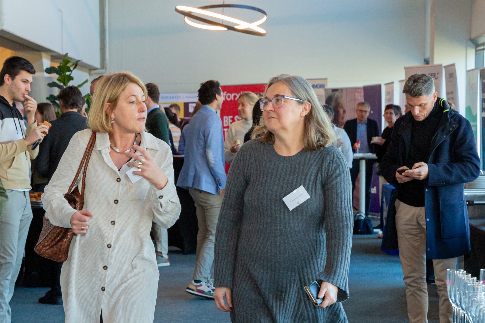 Mensen die gezellig met elkaar praten tijdens een informeel netwerkevenement binnenshuis, met een aantal deelnemers op de achtergrond.