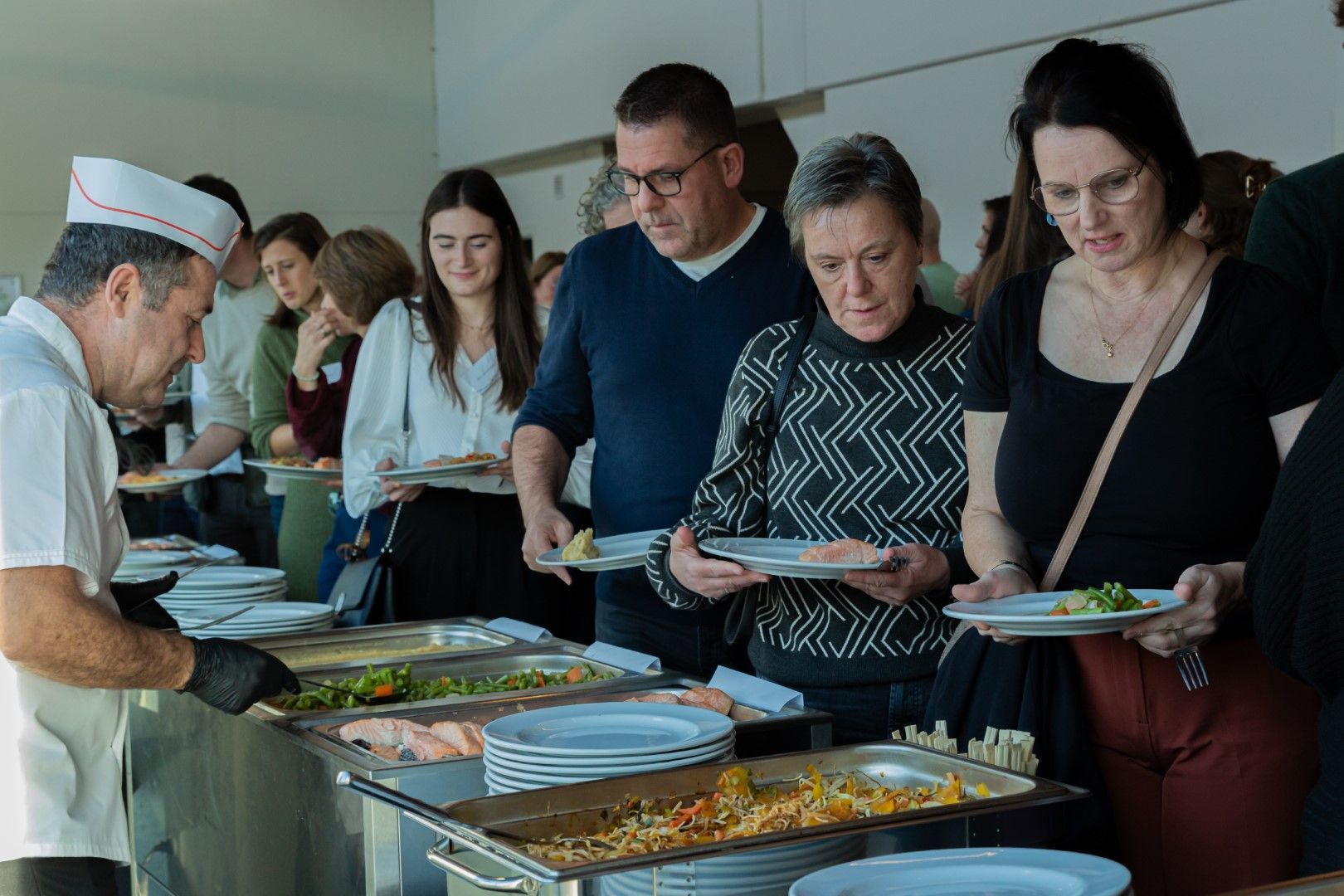 Mensen scheppen zelf hun salades en eten op bij een buffet.