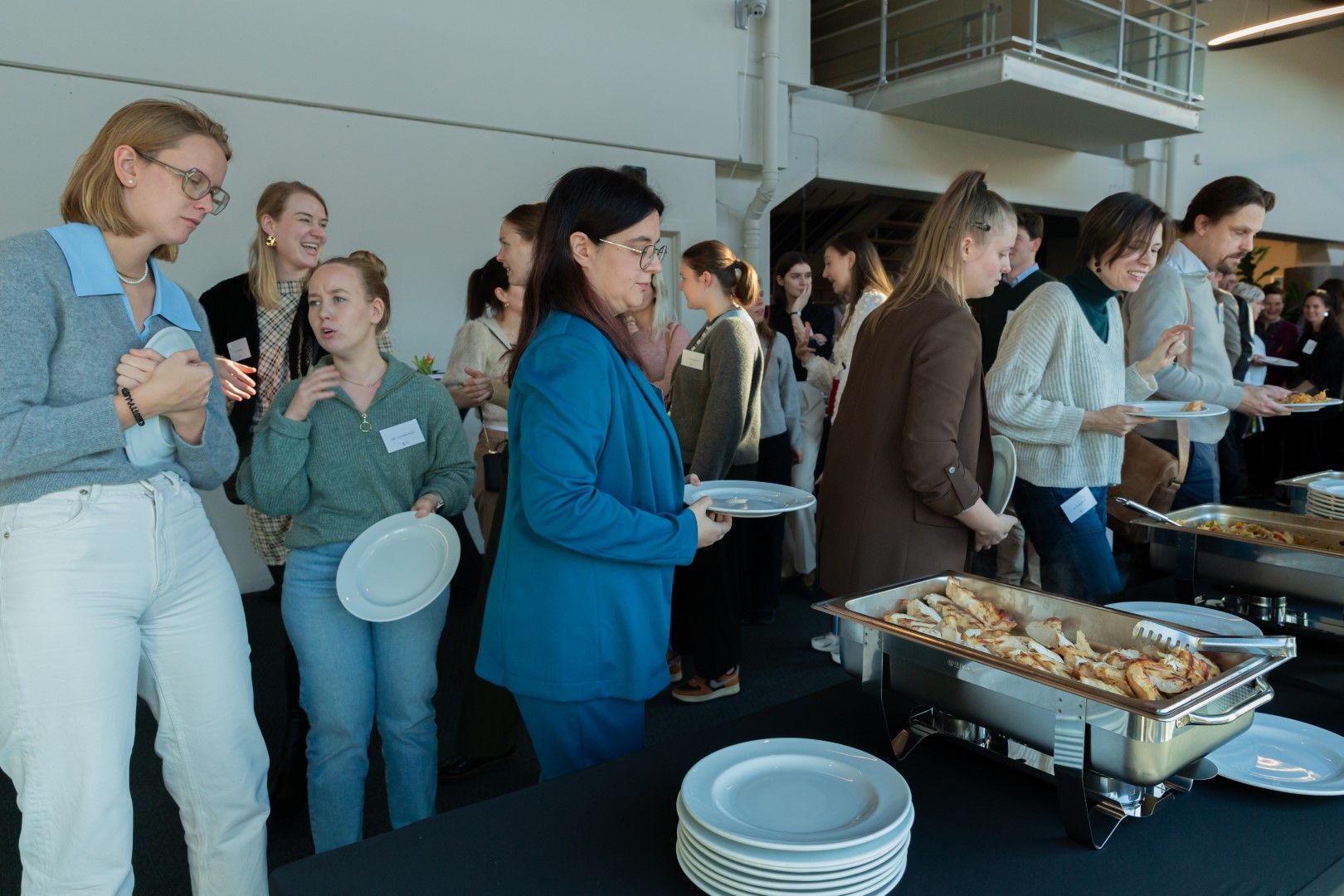 Mensen stonden in de rij bij een buffet en schepten zelf hun eten op tijdens een evenement binnenshuis.