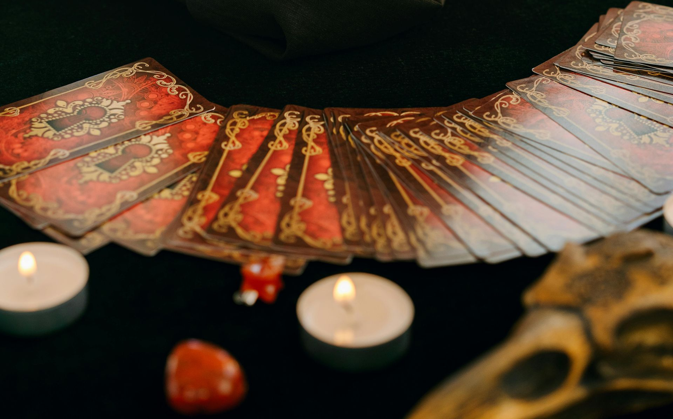 Decorative red fan-style spread with lit candles and a small skull on a dark surface