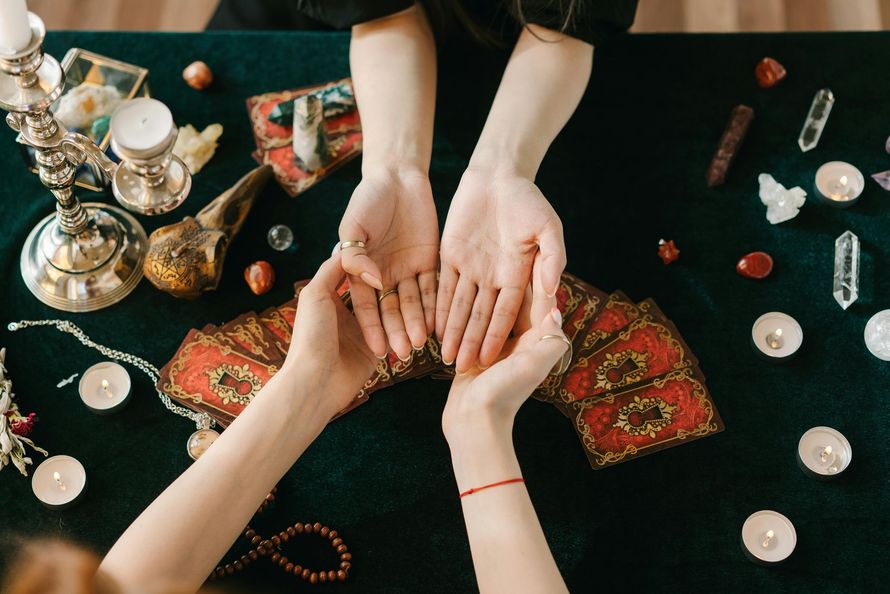 Hands receiving a henna tattoo on a dark cloth, with jewelry and candles nearby