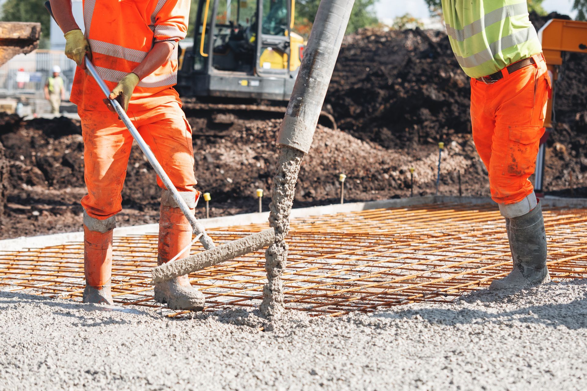 Concrete driveway contractor overseeing concrete pouring at a construction site with a pump.