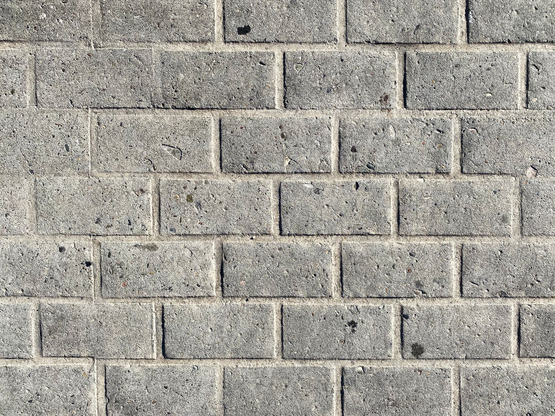 Gray concrete paver walkway with rectangular interlocking bricks in a running bond pattern. Gray concrete paver walkway with rectangular interlocking bricks in a running bond pattern.