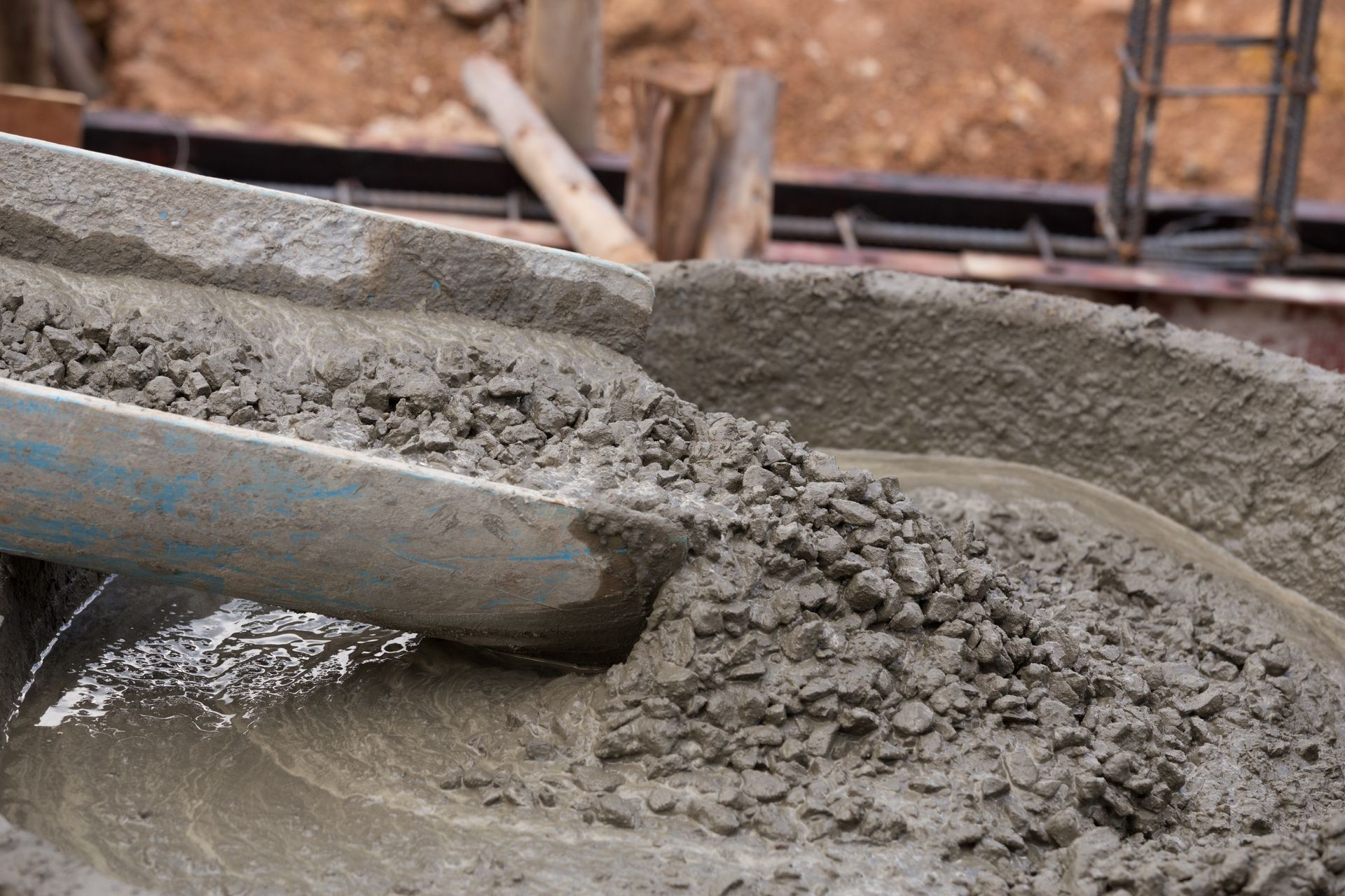 Wet concrete pouring from a chute into a construction form during a building project.