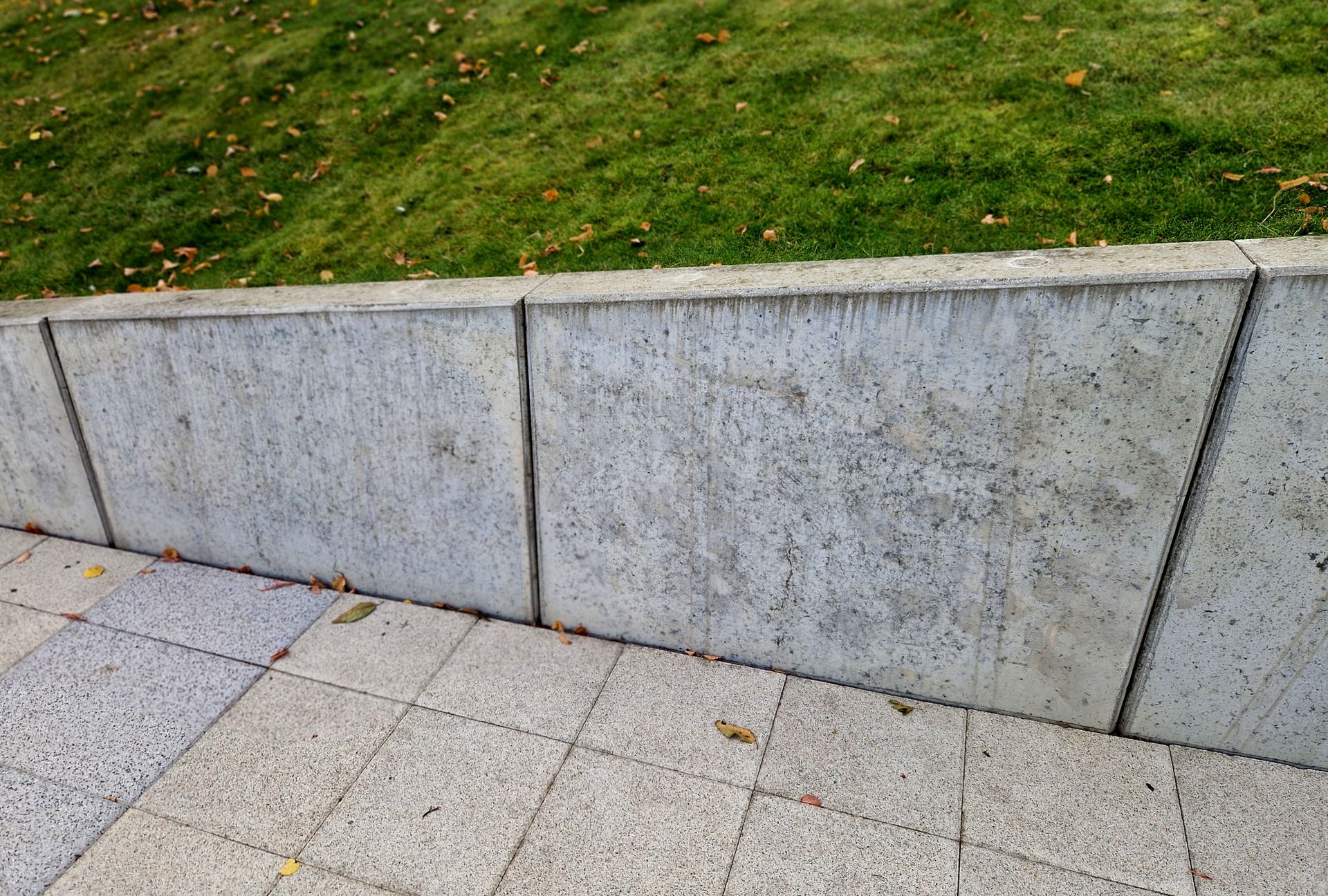 Gray Concrete Wall and Sidewalk Bordering a Grassy Slope — Tucker, GA — A-1 Driveway Replacement Company