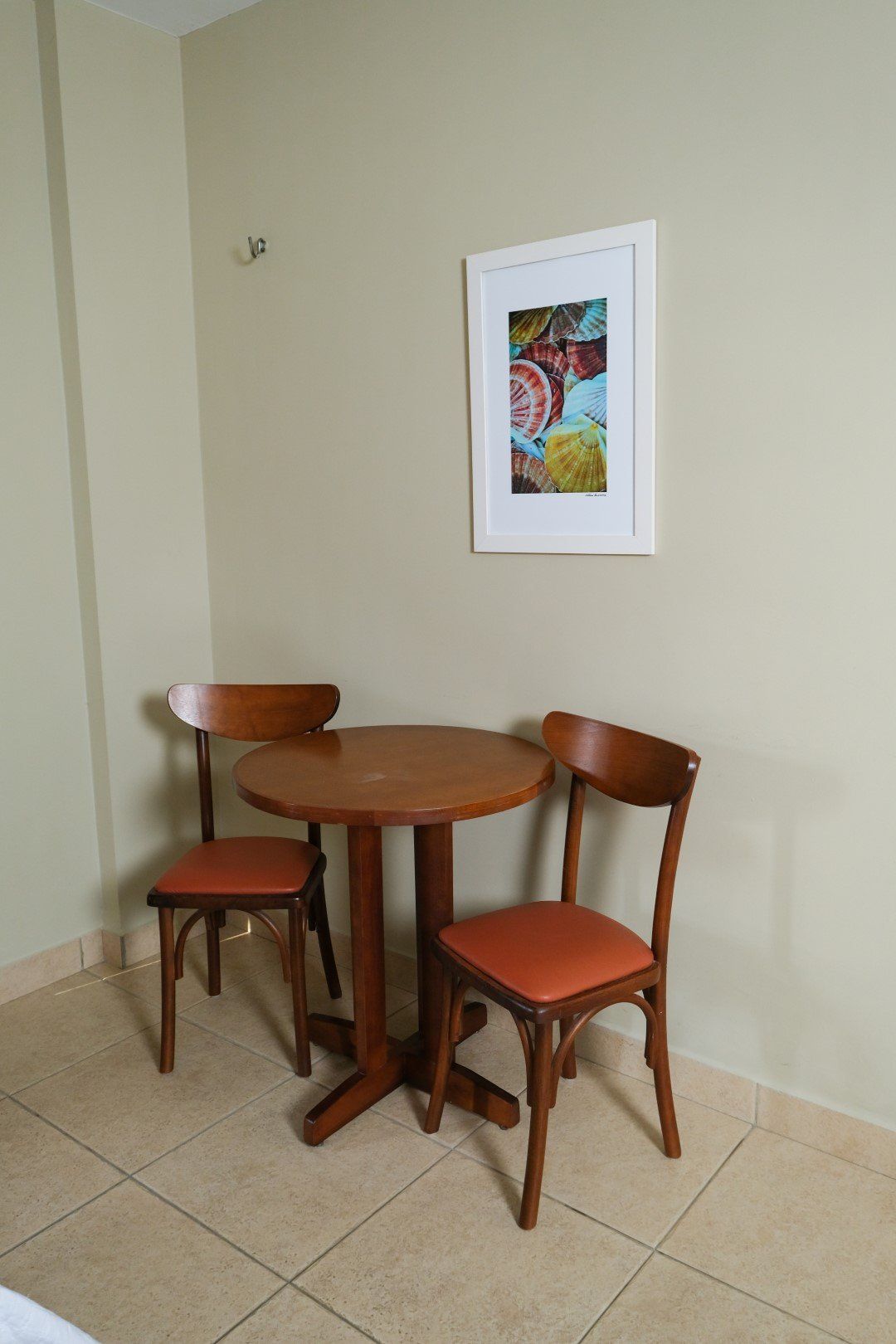 Uma pequena mesa e cadeiras em uma sala com um quadro na parede.