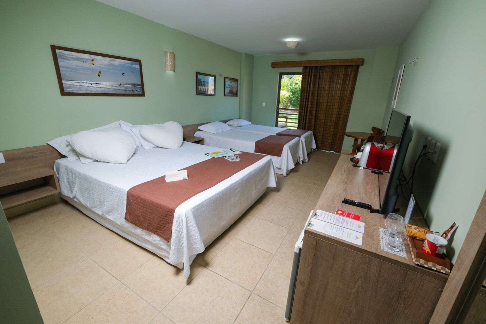 Um quarto de hotel com duas camas e uma televisão.