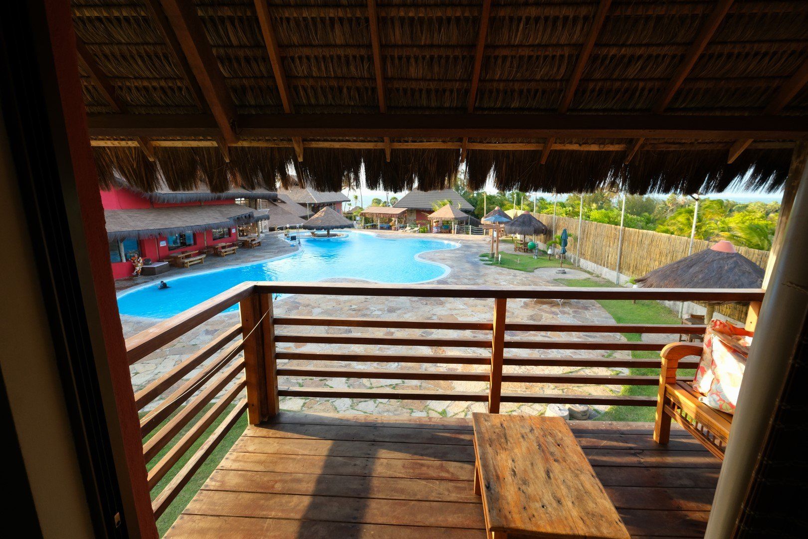 Uma varanda com vista para uma piscina com telhado de palha
