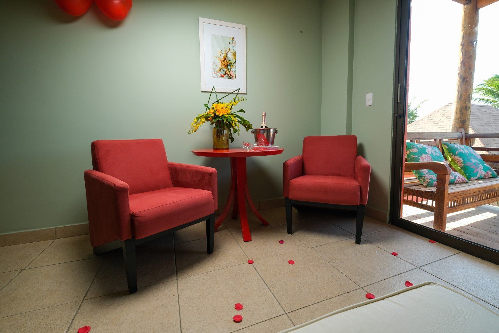 Uma sala de estar com duas cadeiras vermelhas e uma mesa com flores.